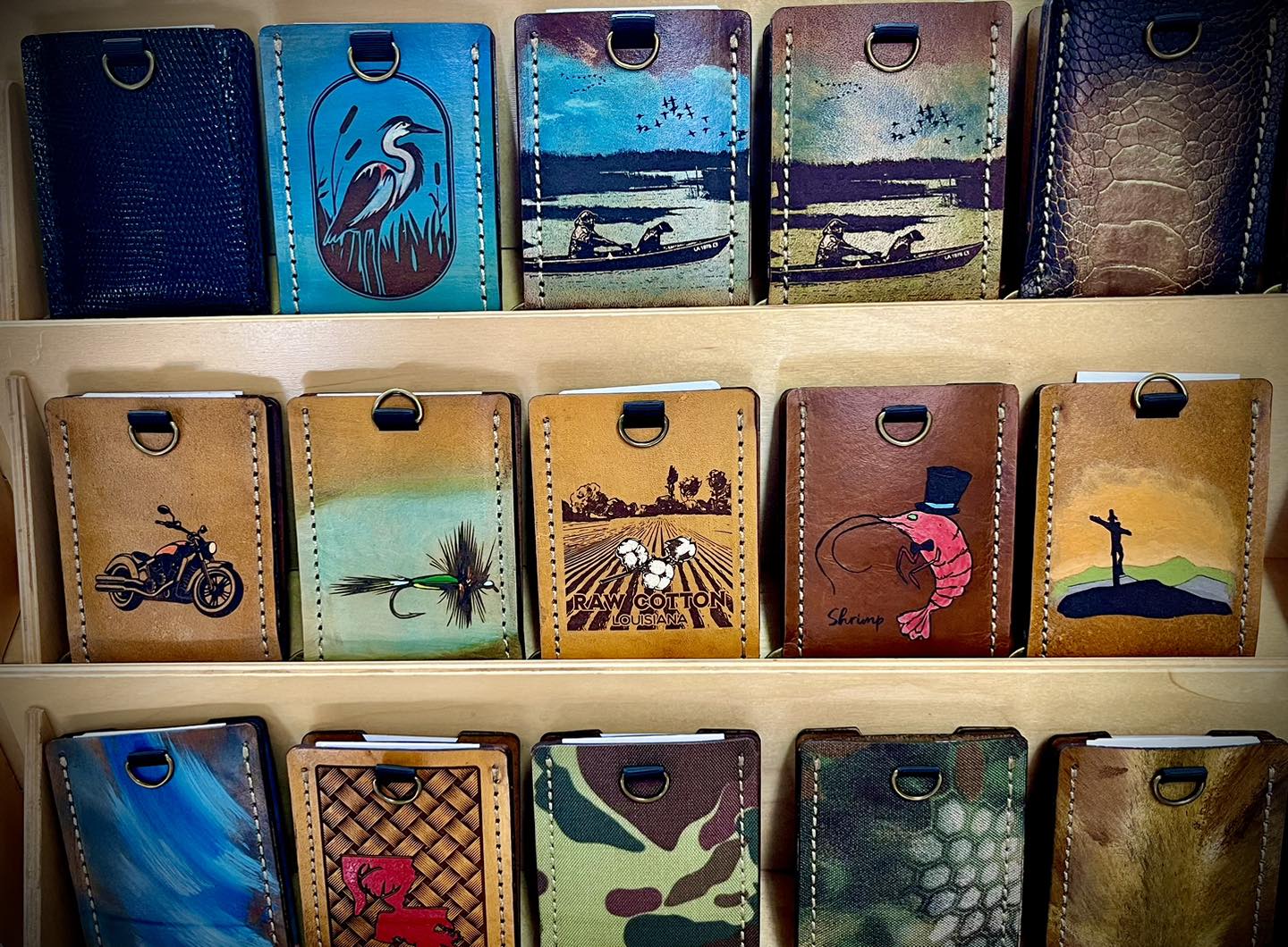 Painted and custom leather card holders arranged on a display shelf.